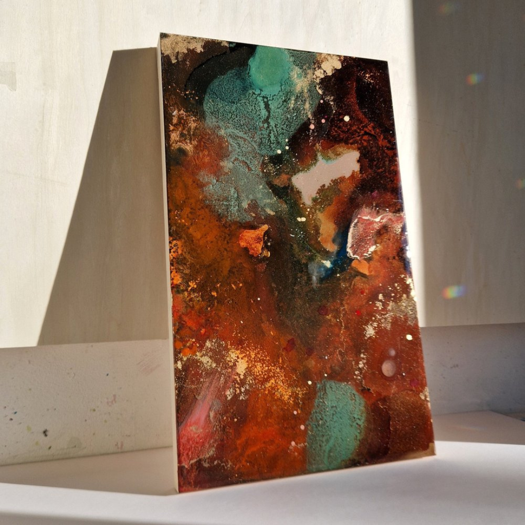 Abstract resin painting with red, orange, black, and teal colors, splattered and blended on canvas, leaning against a wall with sunlight casting a shadow. Created by UK resin artist Katie Alize Art. Leo star sign art, Leo astrology art, Leo fire sign