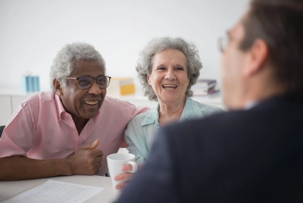 A happy old couple laughing or smiling while talking to an advisor