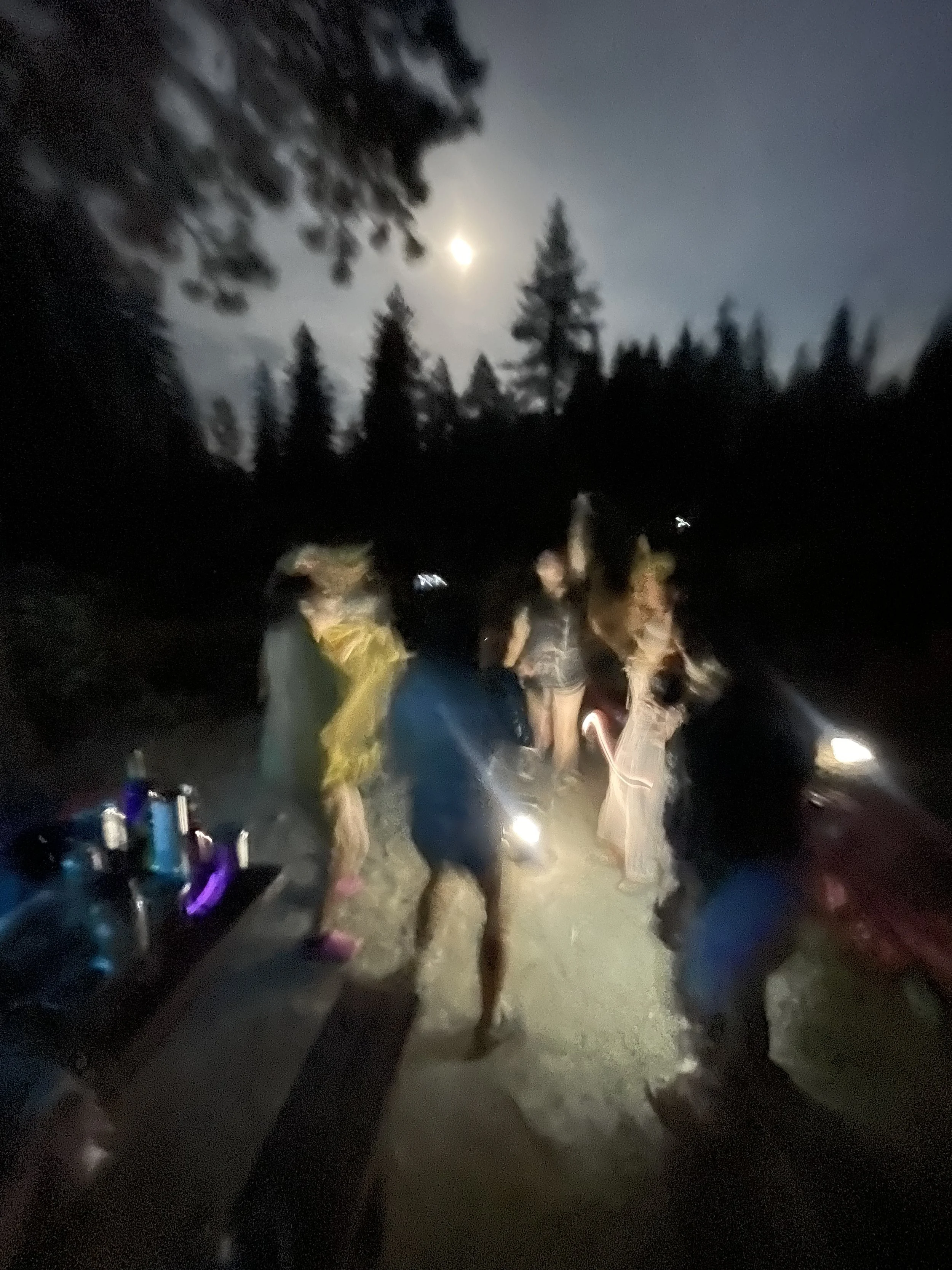 mujeres dancing outside a lake at night under the full moon