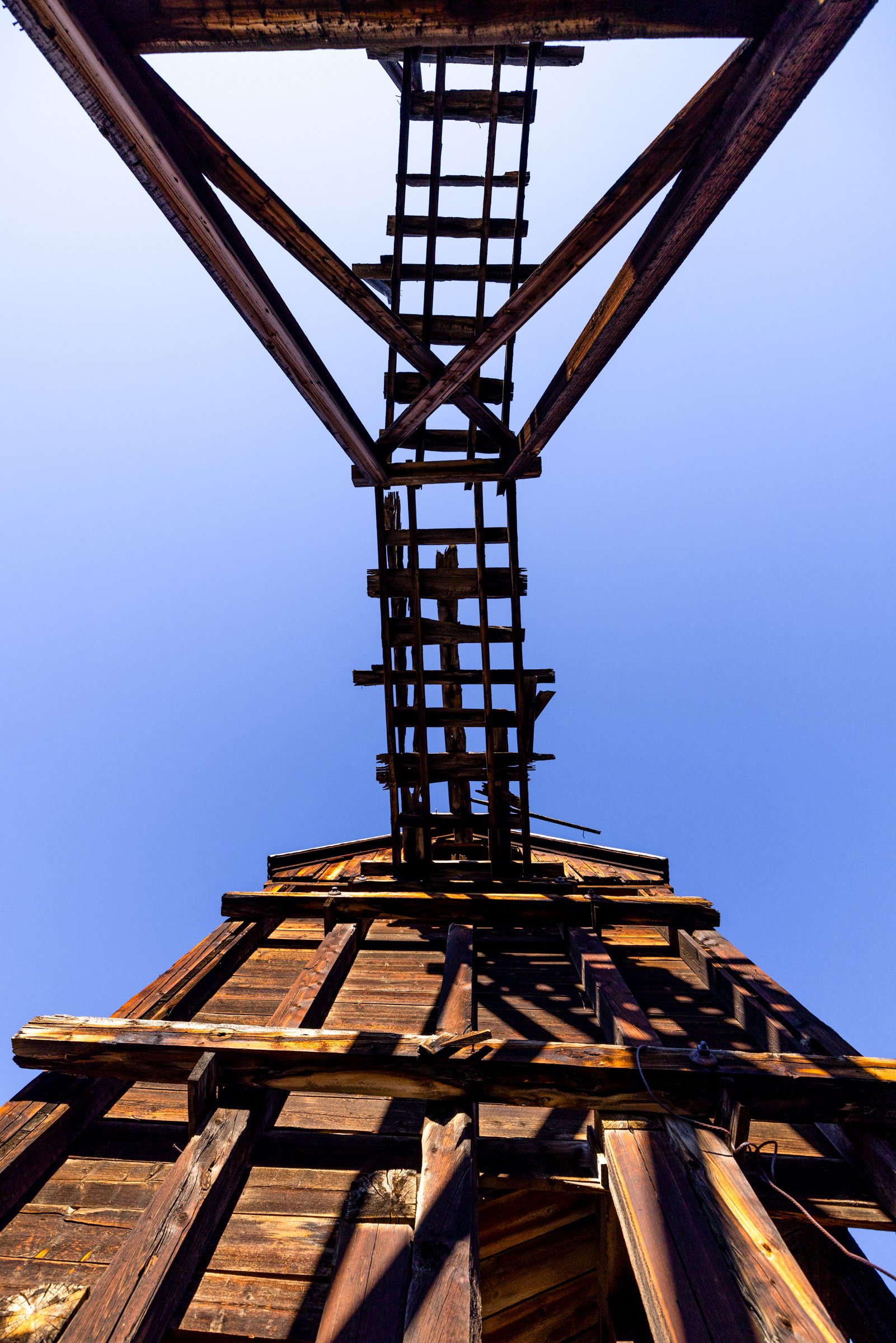 Least Few Rusty Nails, Leadville, 2024. Rickety tracks remain barely intact showing nails protruding from the old timber. The tracks lead to a wooden ore house near Leadville.