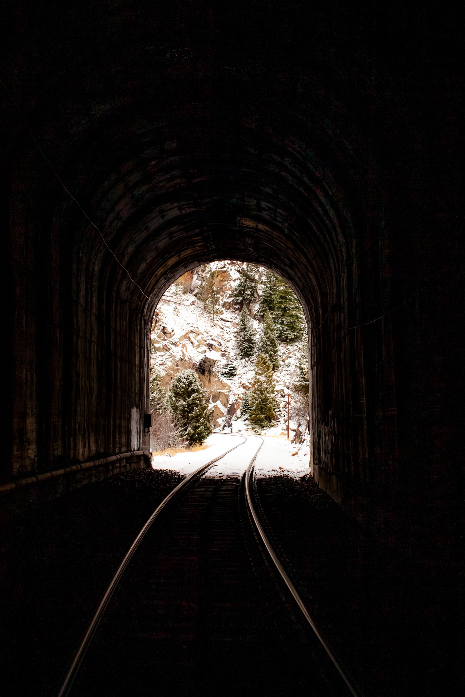 Veins, Front Range, 2021. A single pair of train tracks pierce through the Front Range mountains in a tunnel that is still used to this day for coal, freight, and passenger travel.