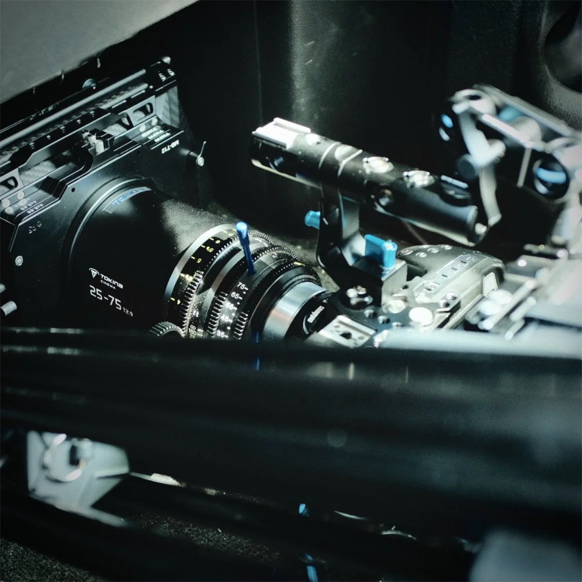 Close-up of a professional cinema camera setup with a TECINA lens and mounted accessories.