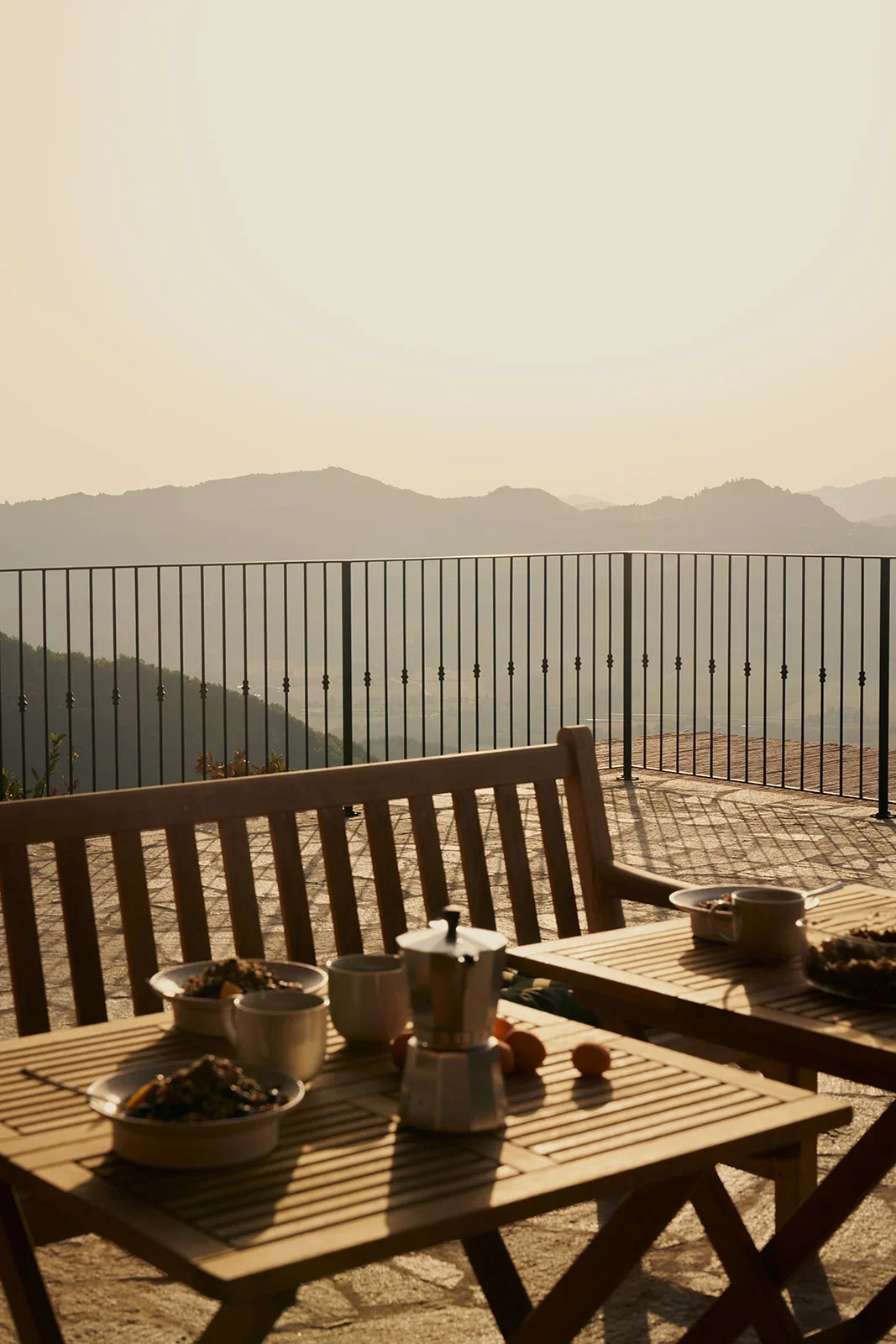 Outdoor table with breakfast items on a patio, overlooking mountains and hazy sky in the background.