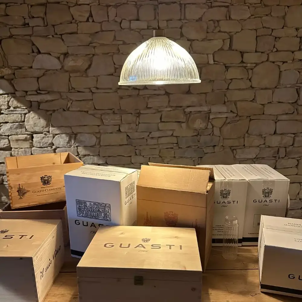 Wooden boxes and cartons on a wooden table with a stone wall background, under a hanging light.