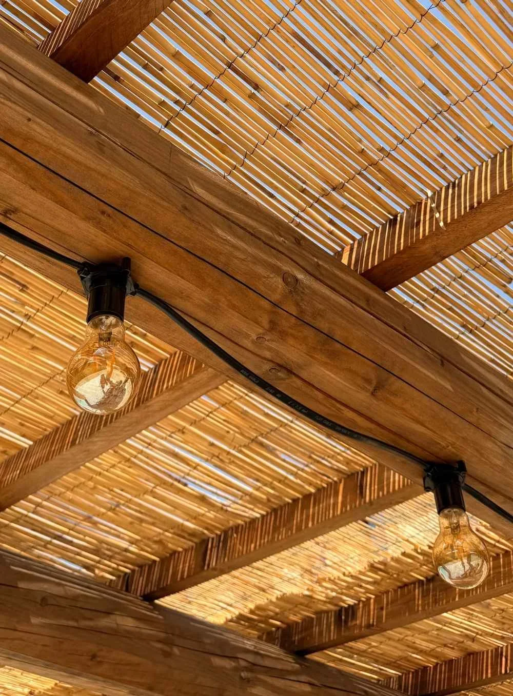 Close-up of a wooden ceiling with hanging light bulbs and a bamboo ceiling cover.