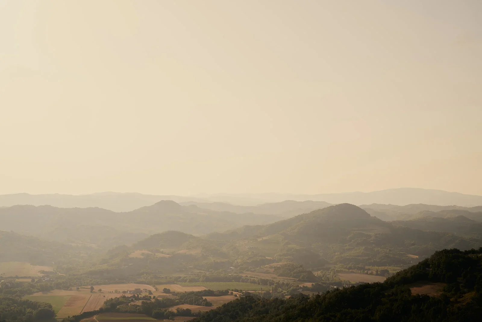 Landscape of rolling hills and mountains under a hazy sky.