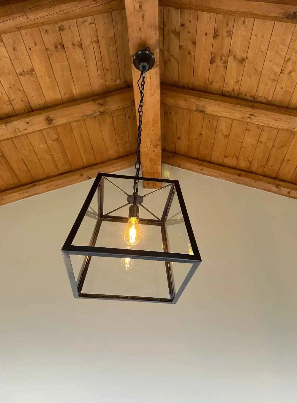 Ceiling light fixture with a Edison bulb in a wooden ceiling with visible beams.