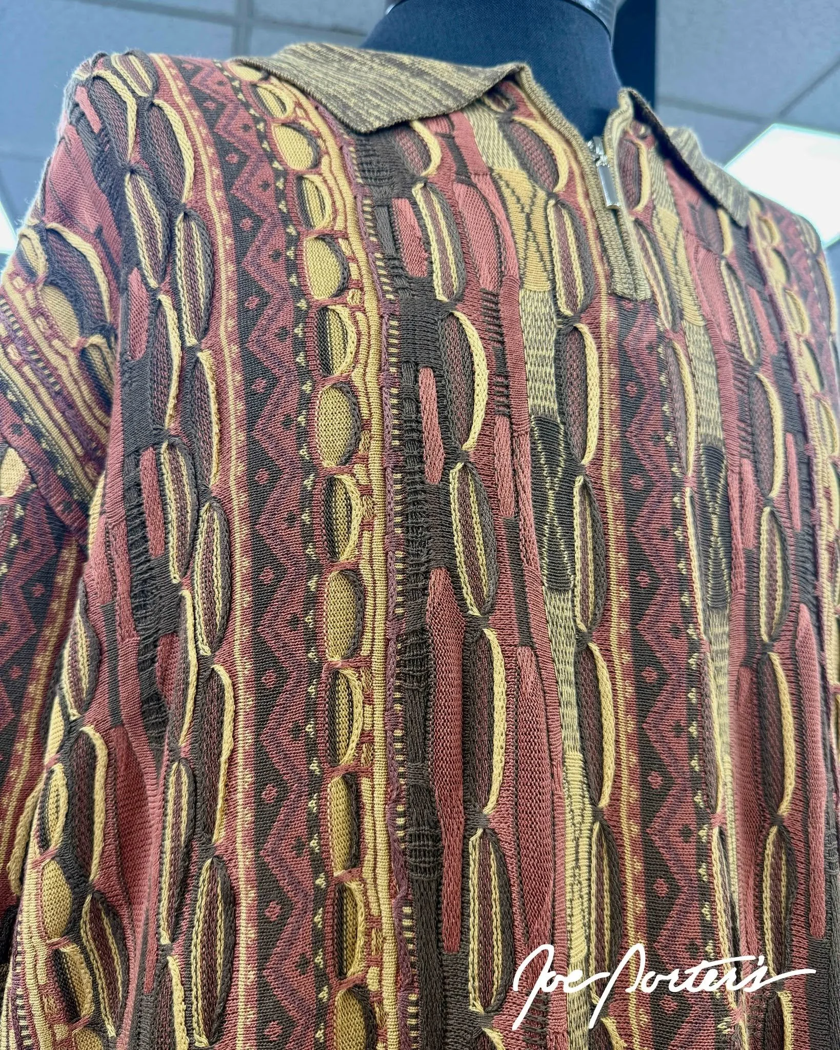 Close-up of a multicolored patterned fabric garment with a zipper and textured collar