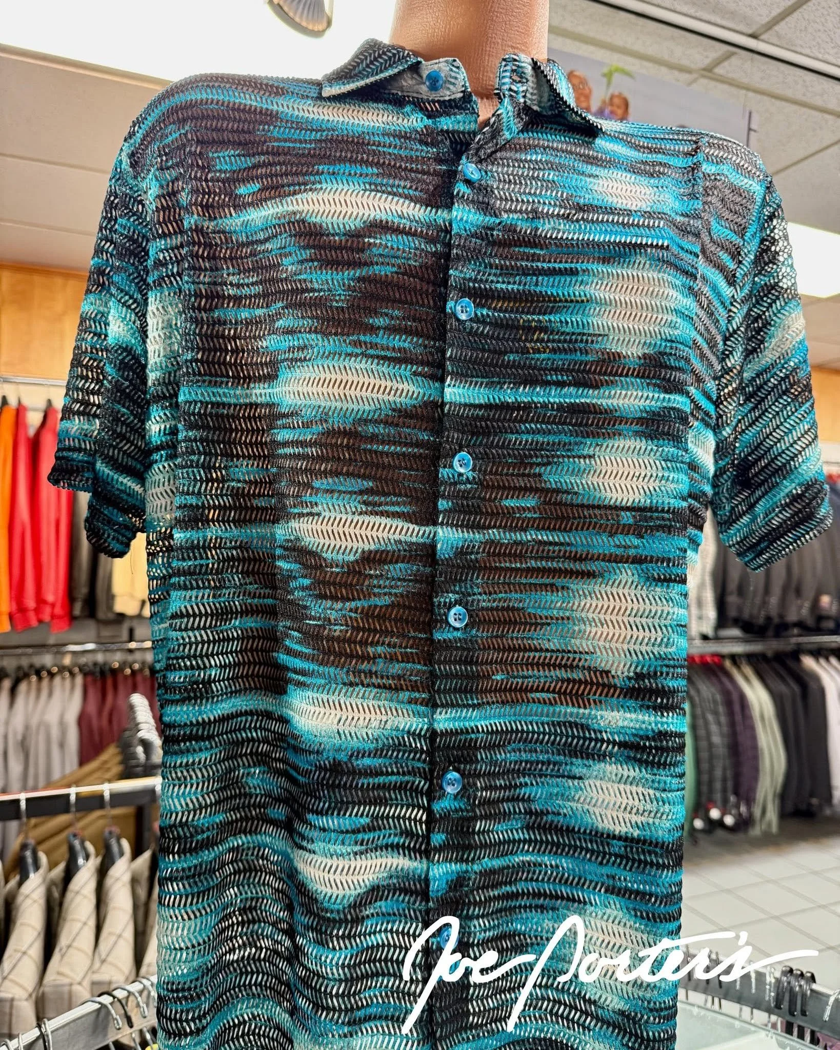 Black, turquoise, and white patterned long-sleeve button-up shirt displayed in a clothing store