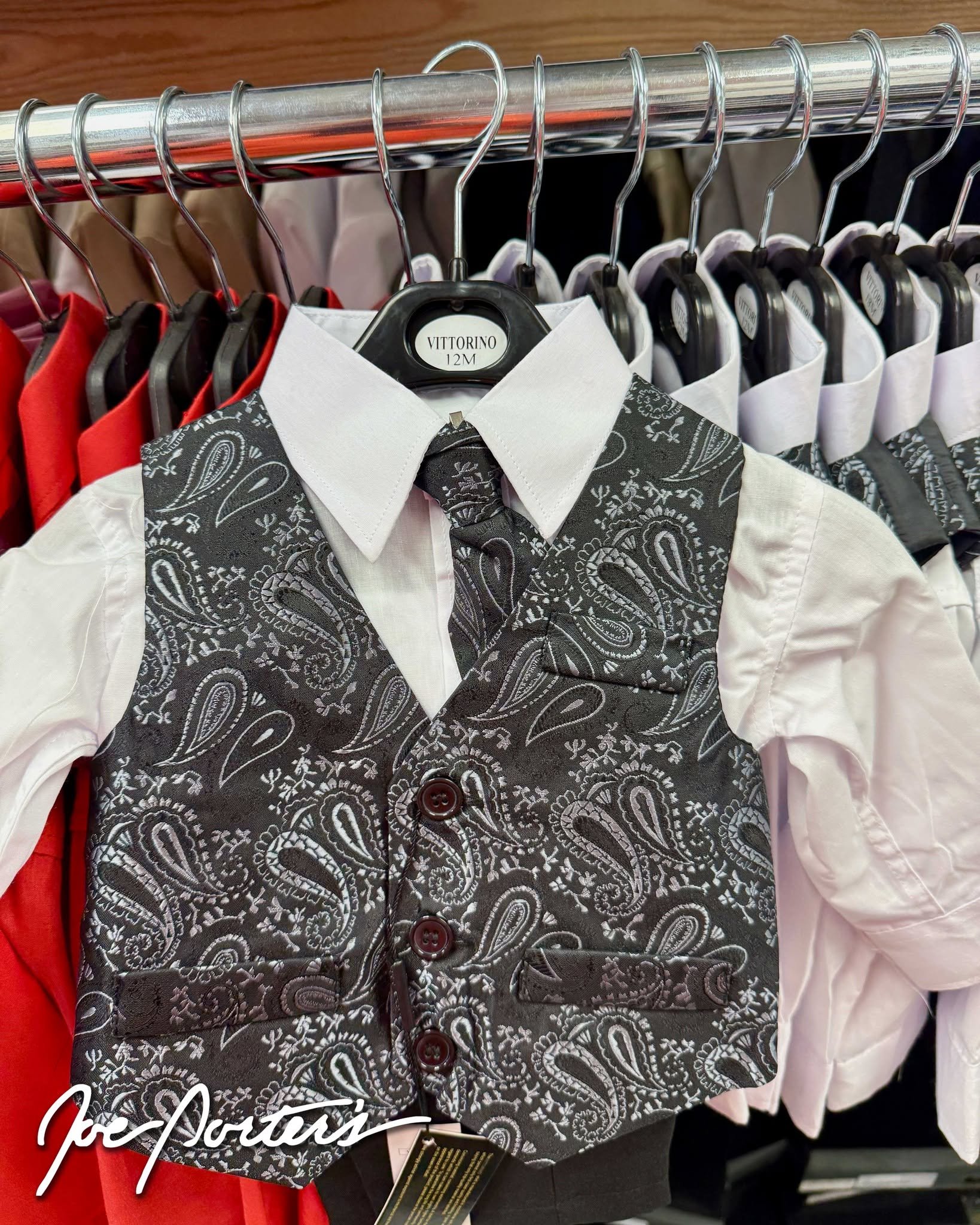 Children’s formal outfit with a gray paisley vest and tie over a white collared shirt on a clothing rack