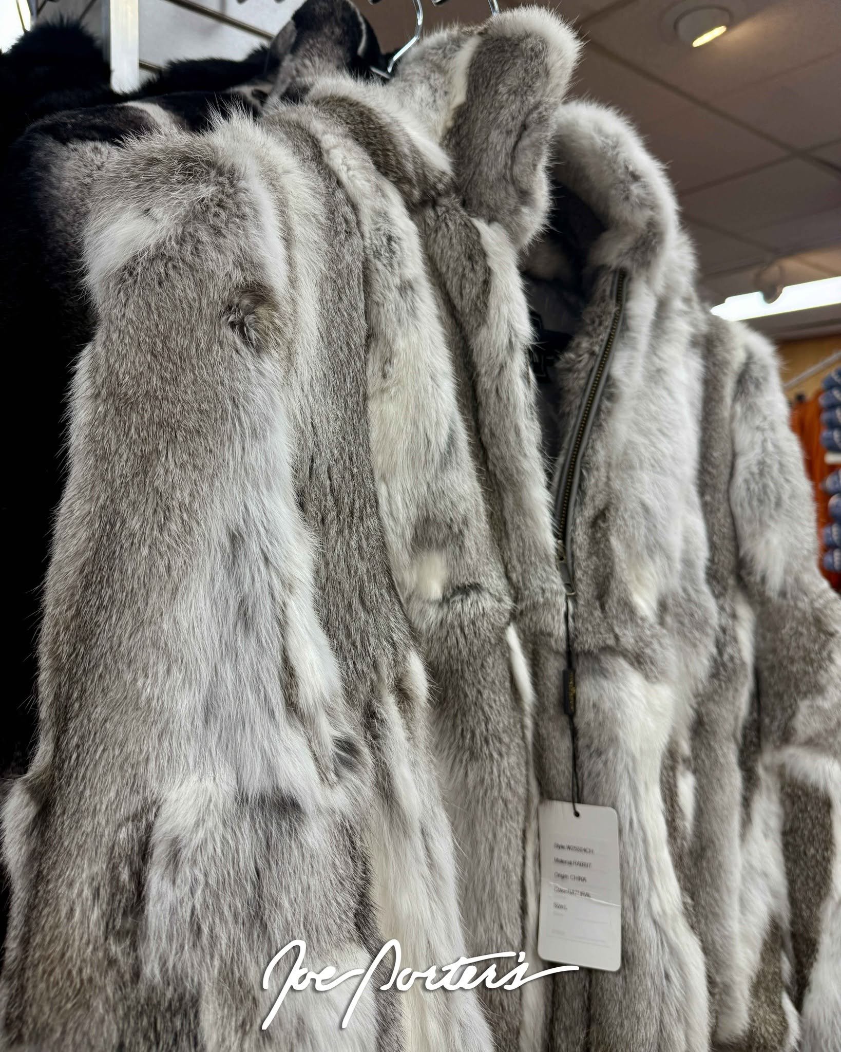 Gray and white fur coats displayed on hangers in a clothing store