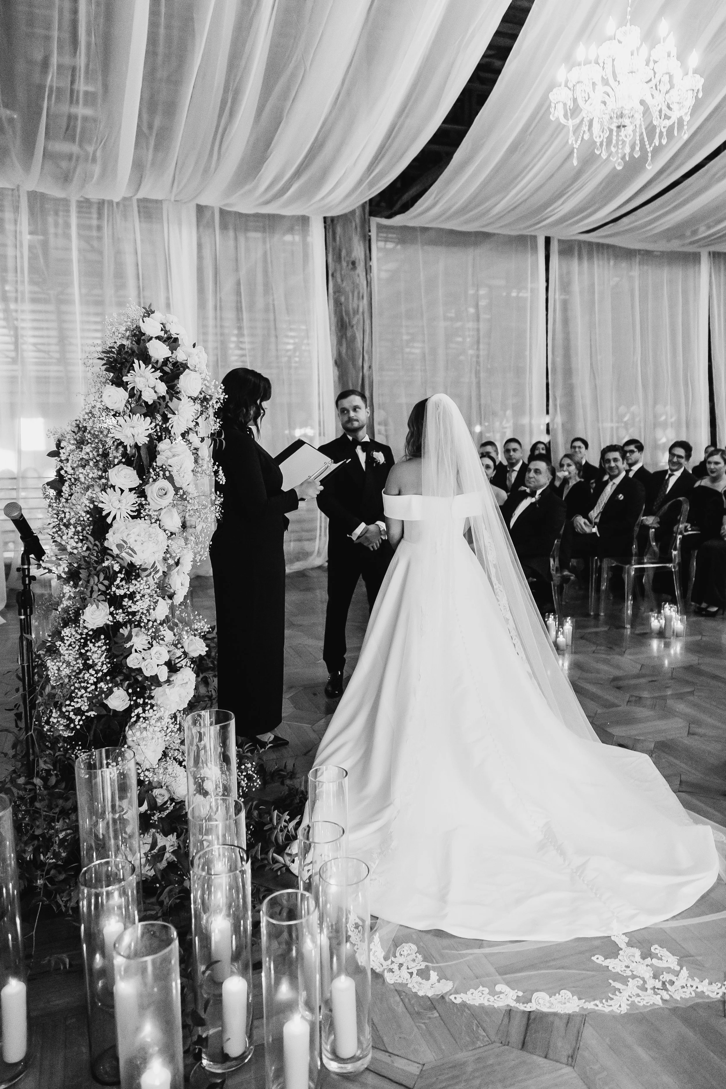 candid black and white photo of bride and groom exchanging vows at indoor winter wedding ceremony at maysara winery