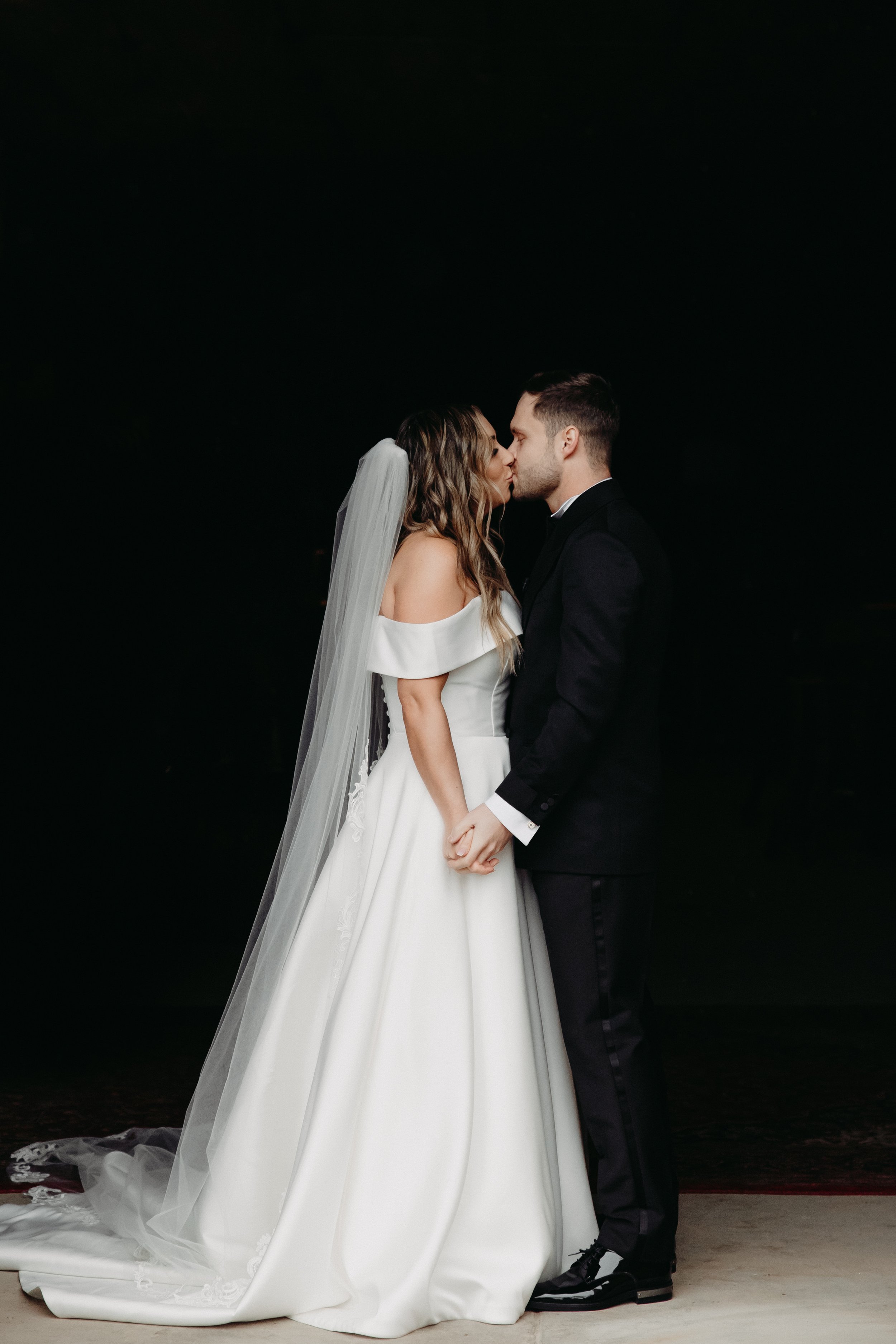 Full body portrait of bride and groom kissing before winter wedding at Maysara Winery