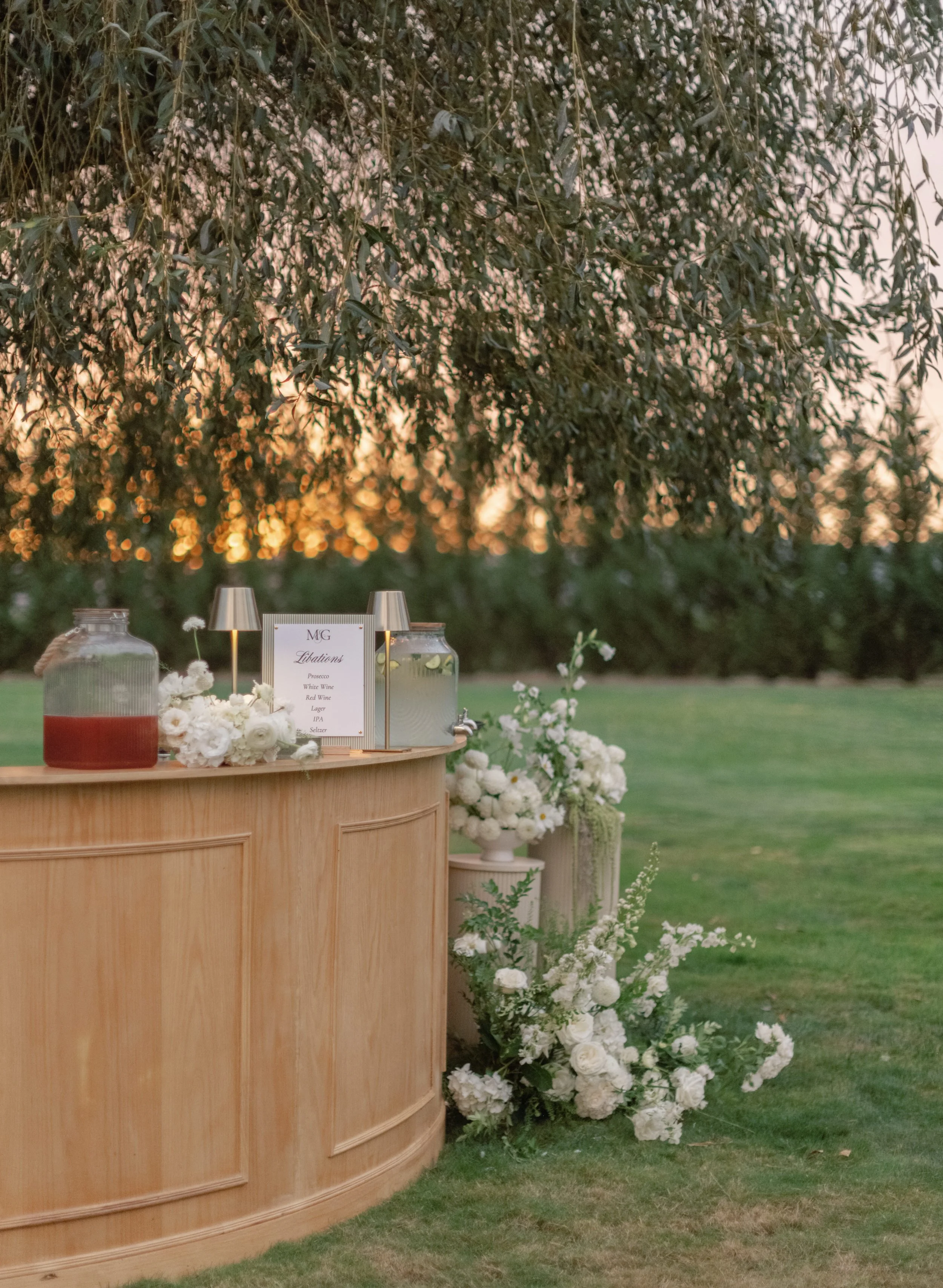 Wedding reception bar at sunset with florals stacked around