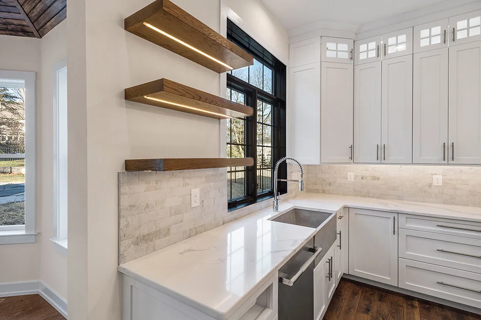 Kitchen with white cabinets, a window, and floating wooden shelves with LED lighting.
