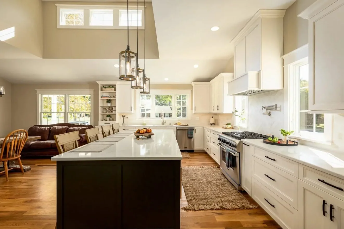 Bright and spacious kitchen with white cabinets, stainless steel appliances, large island with seating, and hardwood floors.
