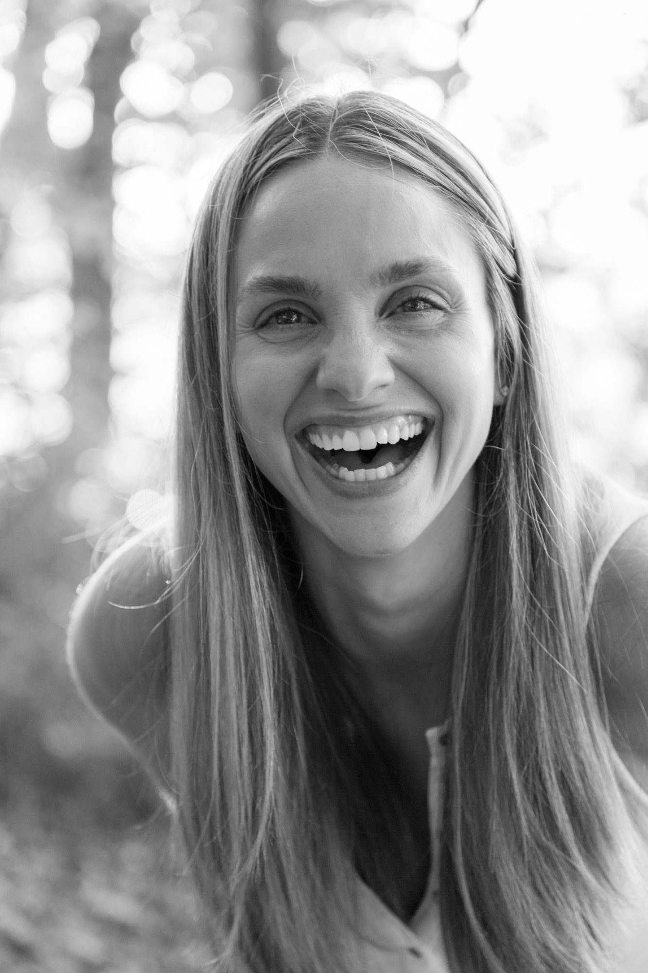 Black and white photo of a woman with long hair smiling and laughing.