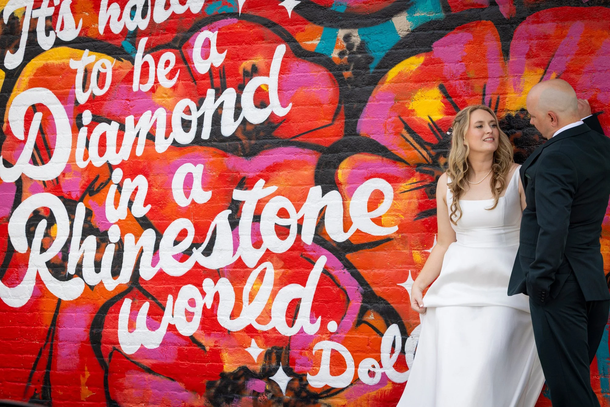 A colorful mural with the words 'It's hard to be aDamned. Whatever.'
