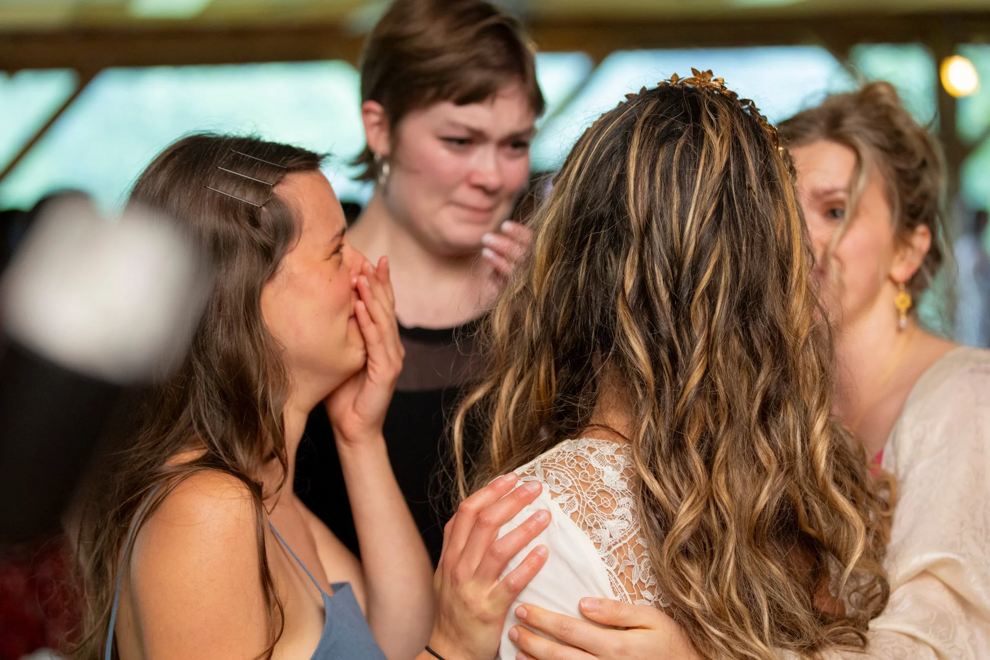 A group of women sharing an emotional moment, hugging and comforting each other at what appears to be a celebration or gathering.