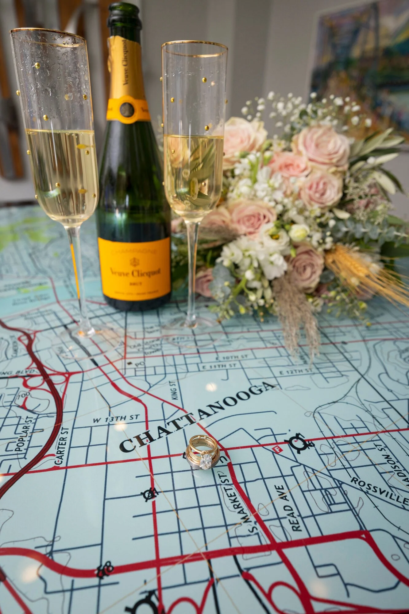Champagne glasses, a champagne bottle, flowers, and a wedding ring arranged on a map of Manhattan, New York City.