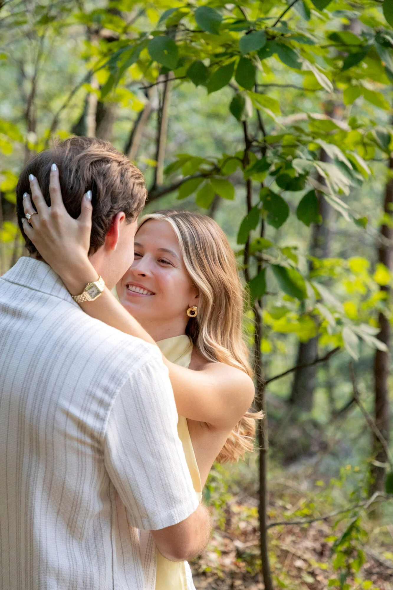 A couple in love embracing each other in a lush green forest, with soft sunlight filtering through the leaves.