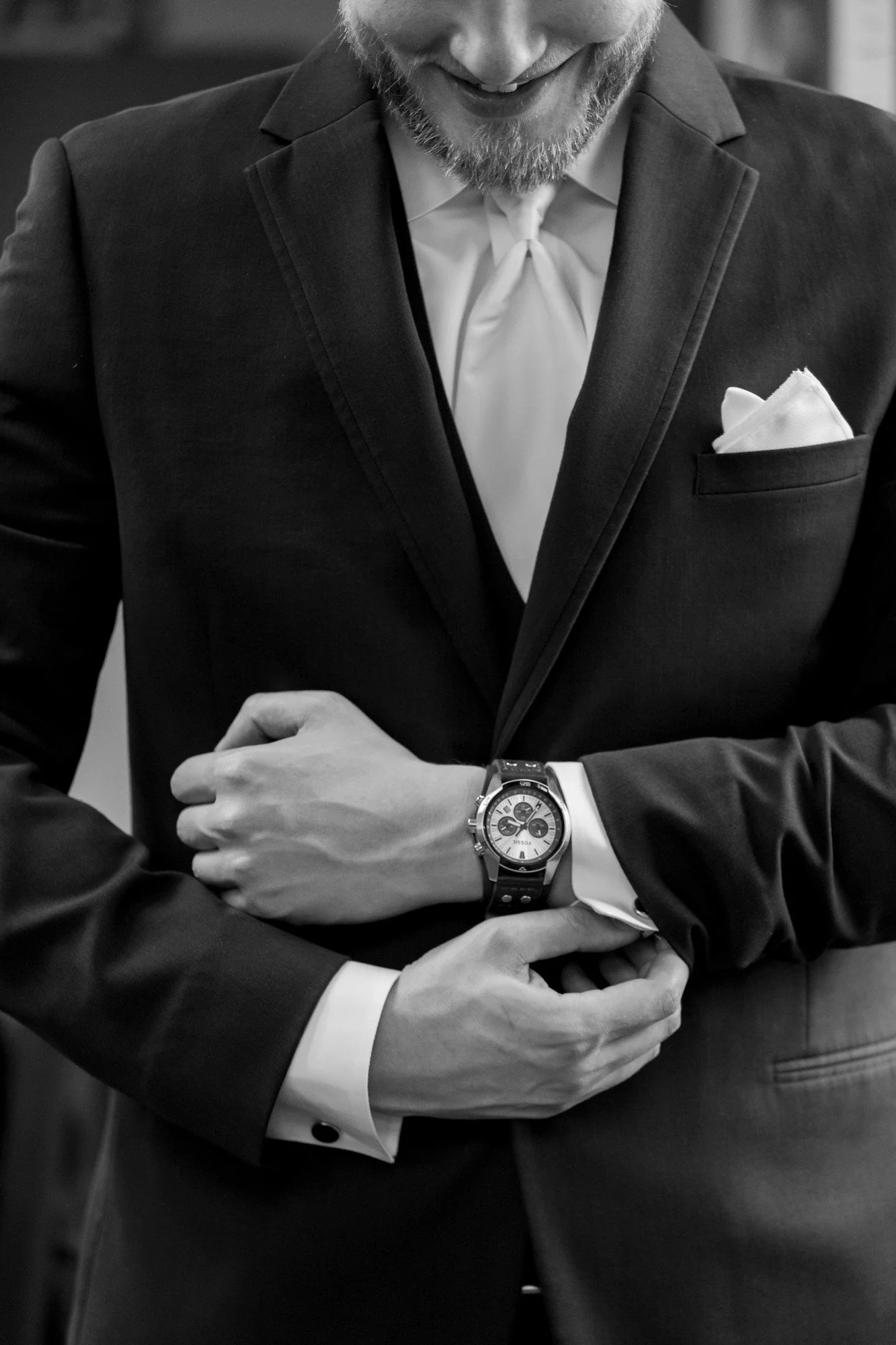 Close-up of a man in a suit adjusting his wristwatch.