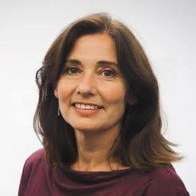 A woman with shoulder-length brown hair smiling, wearing a dark red top, against a plain white background.