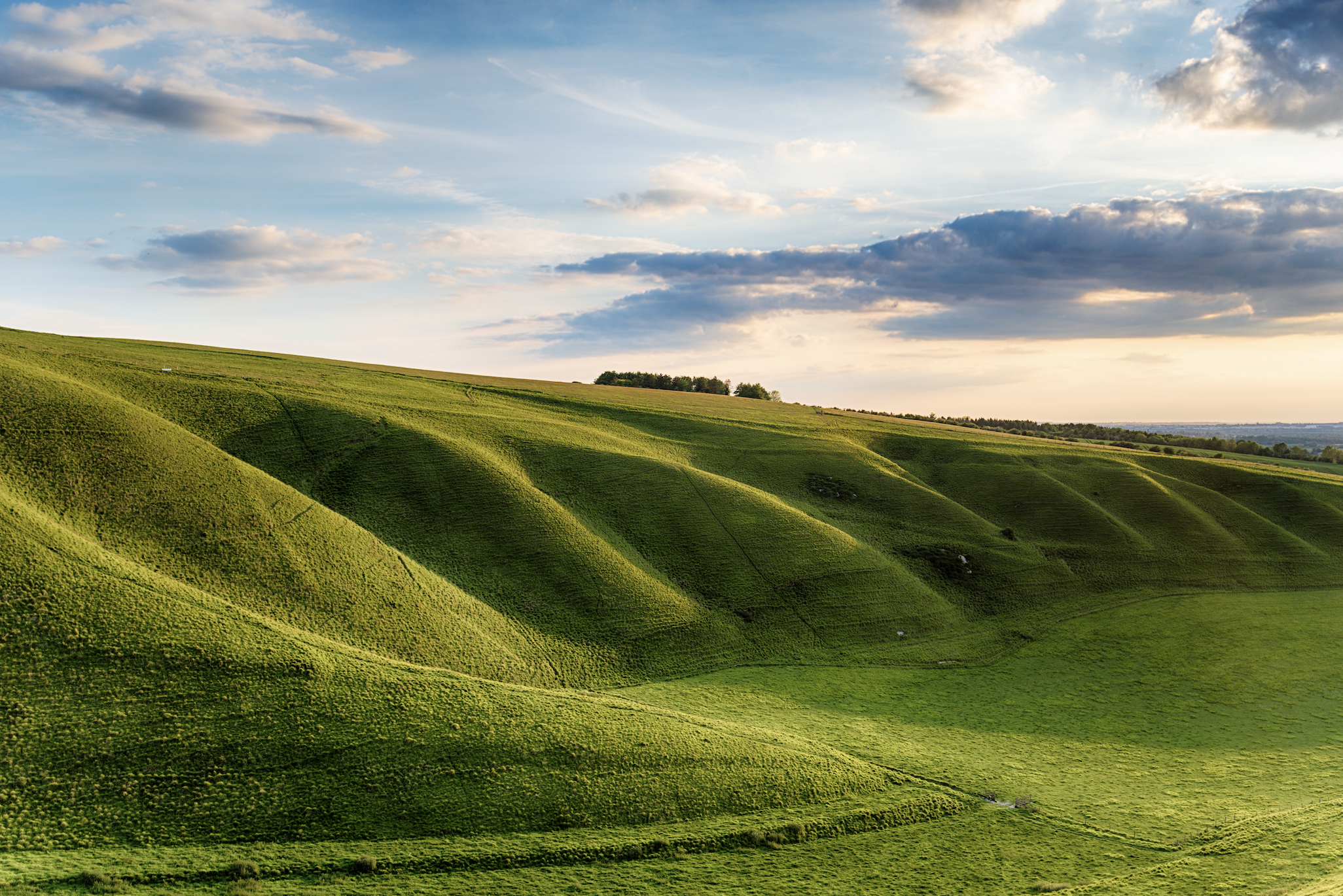 Green rolling hills under a partly cloudy sky.