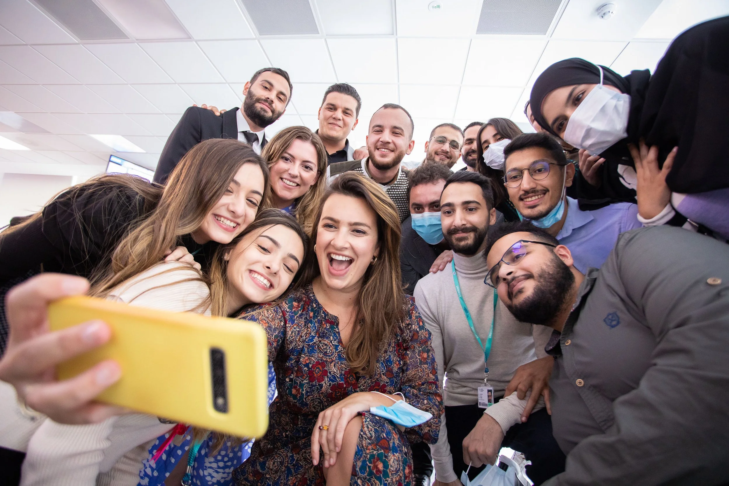 Group of diverse smiling people taking a selfie in an indoor setting.