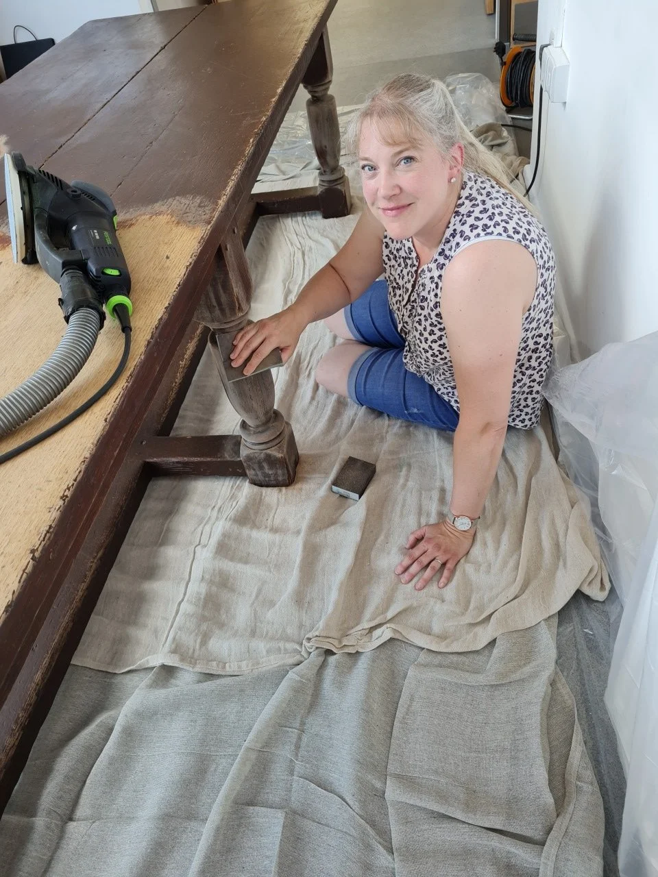 Rebecca Meredith, furniture painter- sanding down the leg of an oak table
