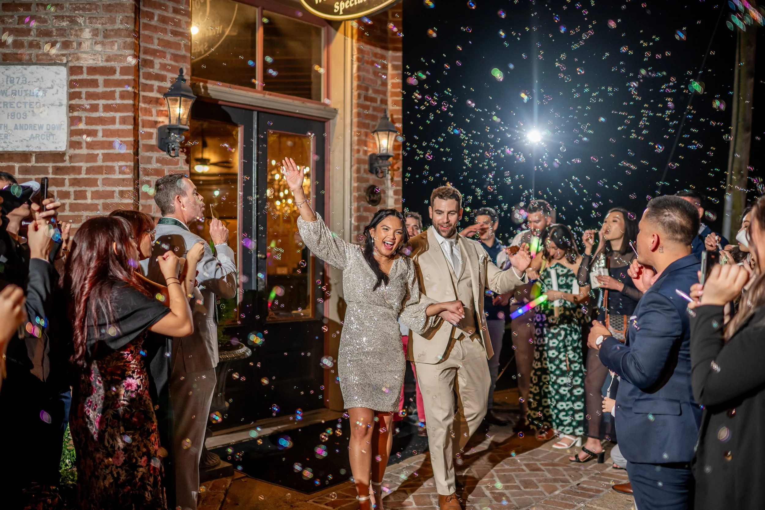 Wedding bubble exit at Butler’s Courtyard in League City Texas with couple celebrating and guests blowing bubbles at night