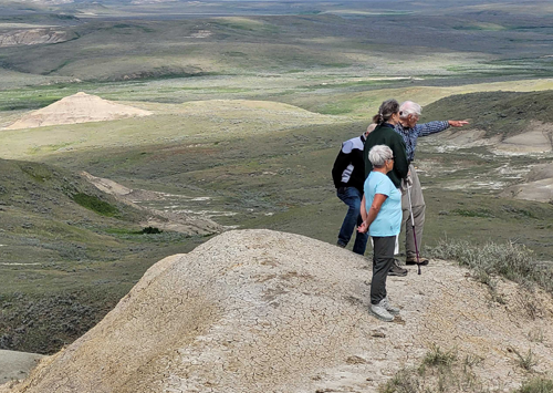 Four people stand on a high hill overlooking Grasslands National Park.