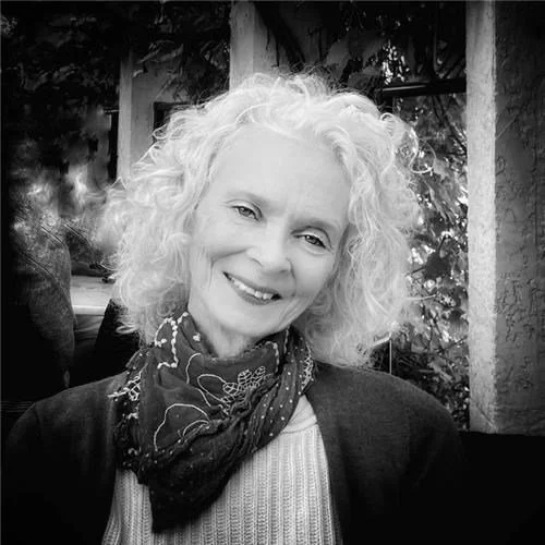 Black and white photo of Joan Brewerton smiling. She has curly hair and is wearing a bandana neckerchief.