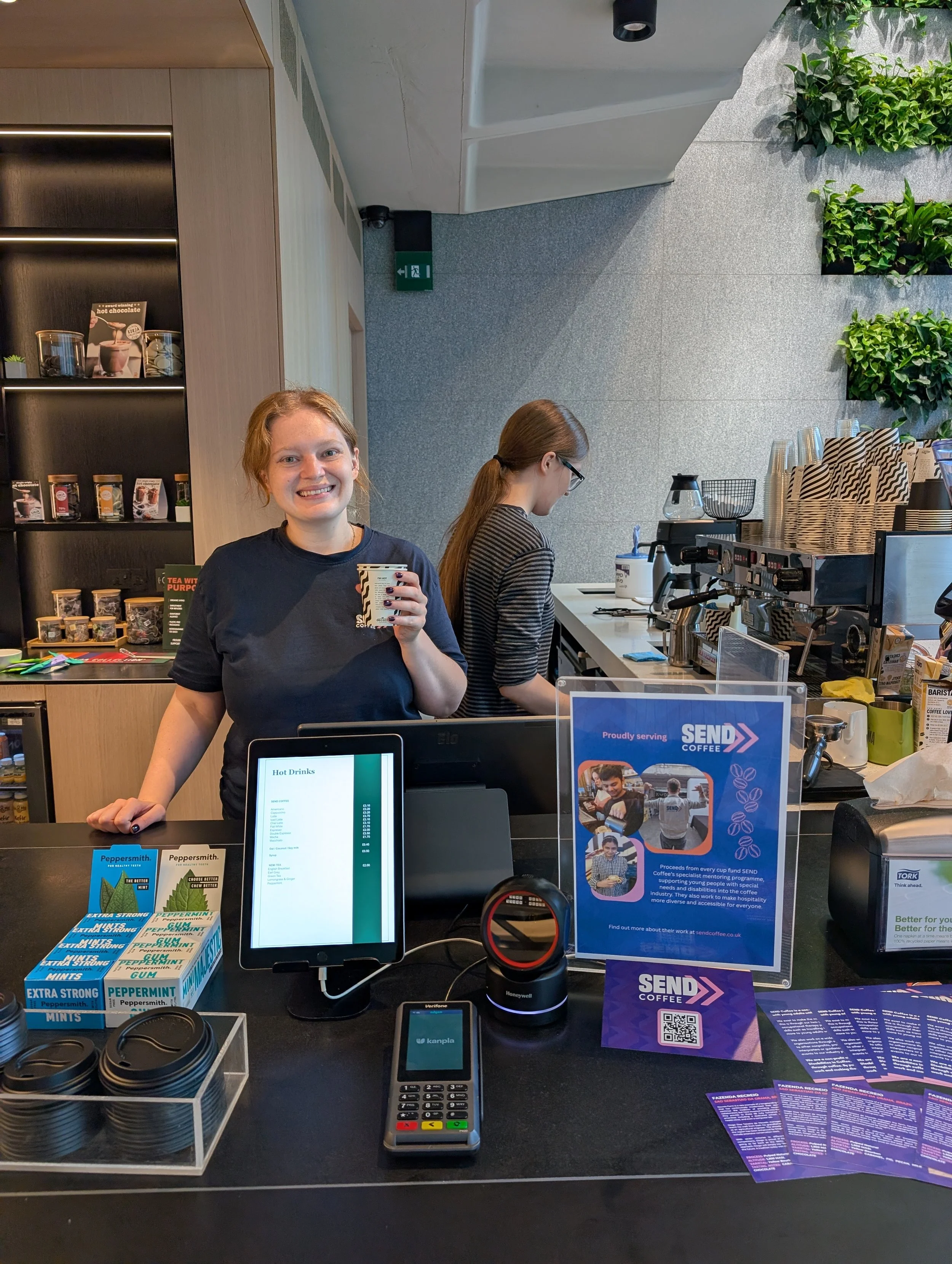 A woman standing behind a coffee bar holding a cup of coffee