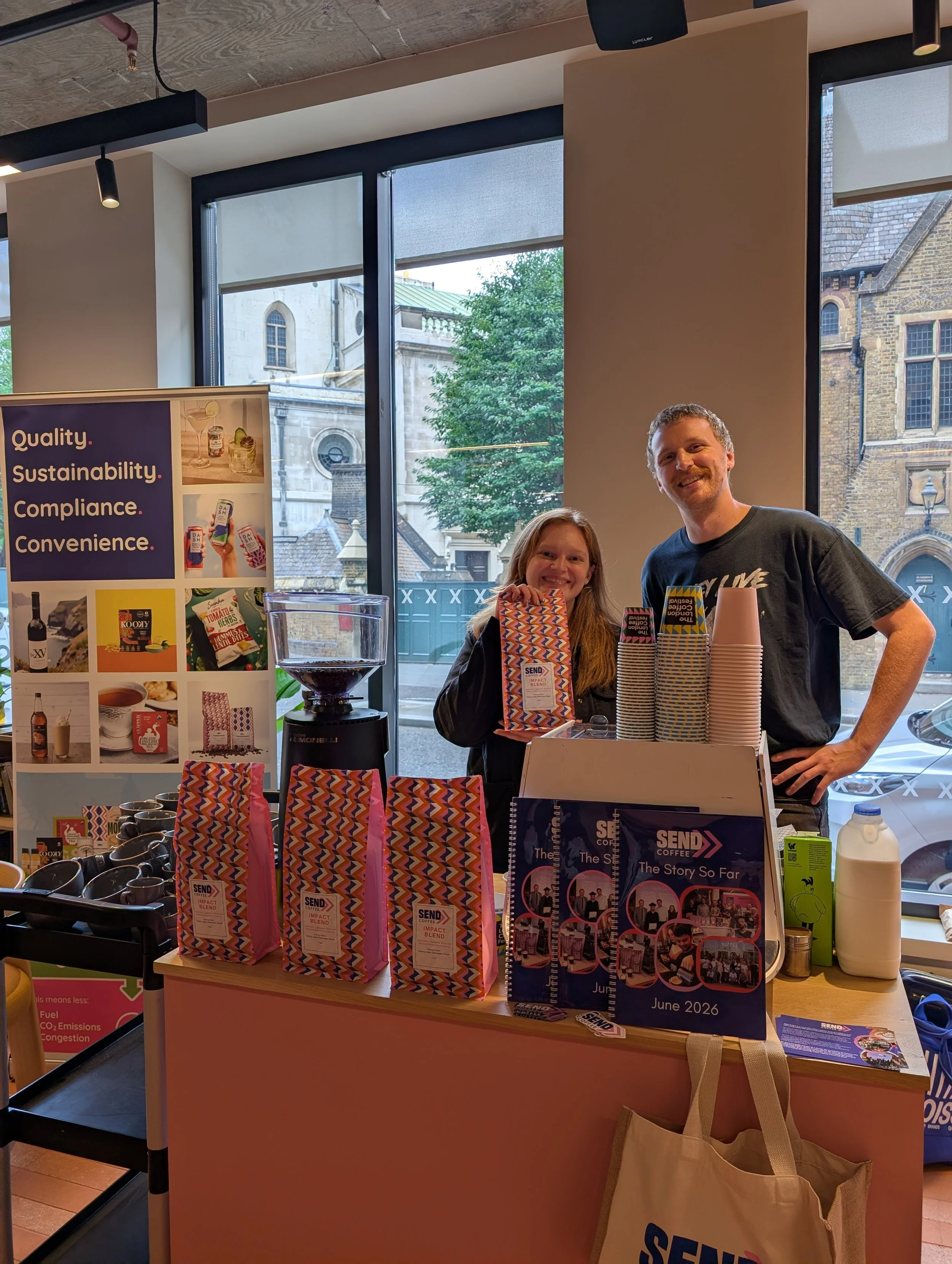 An image of a man and a woman standing behind a pop-up coffee machine at an event