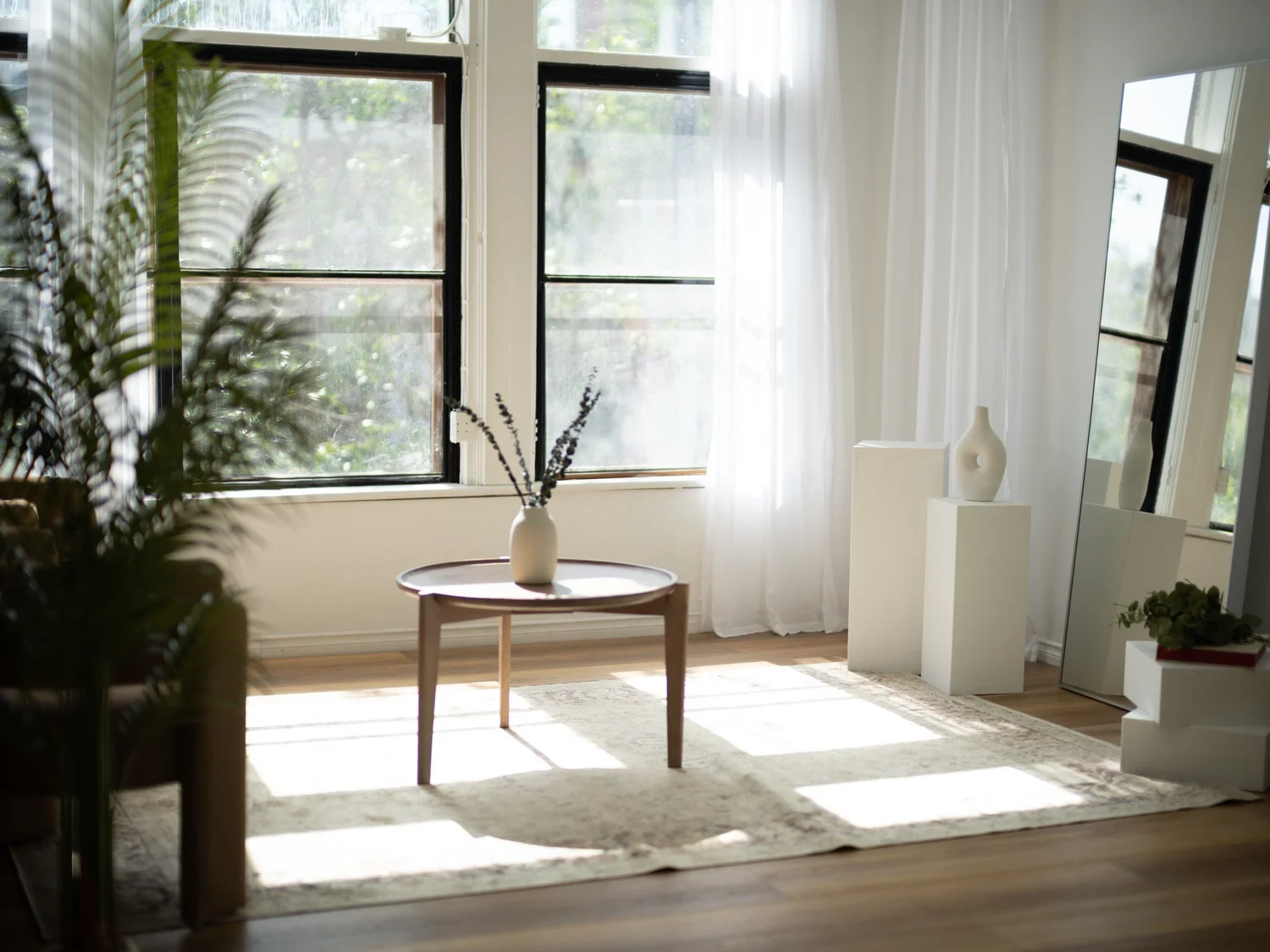The daylight studio at Nomadic Studio Co., with east and south facing windows, sheer curtains and pedestals on a rug