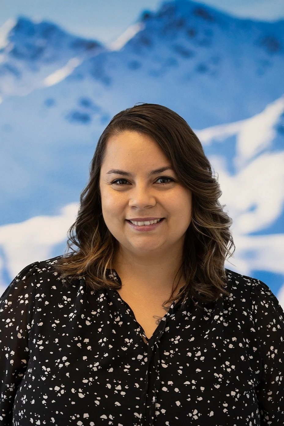 headshot photo of alexis phillips smiling in front of an abstract blue and white background