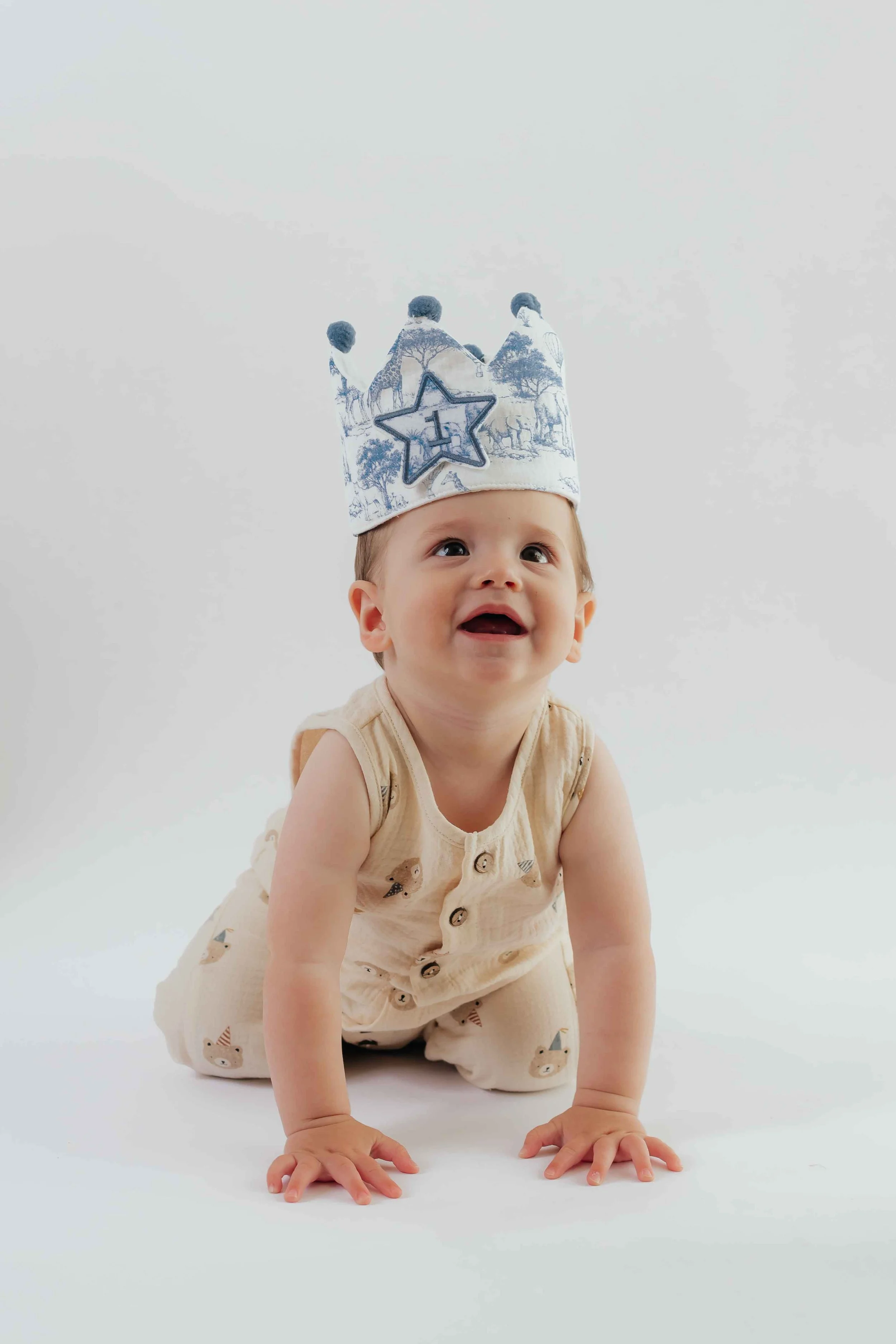 one year old baby boy with safari blue King crown on hands and knees in Bay Area Photographer’s photo studio