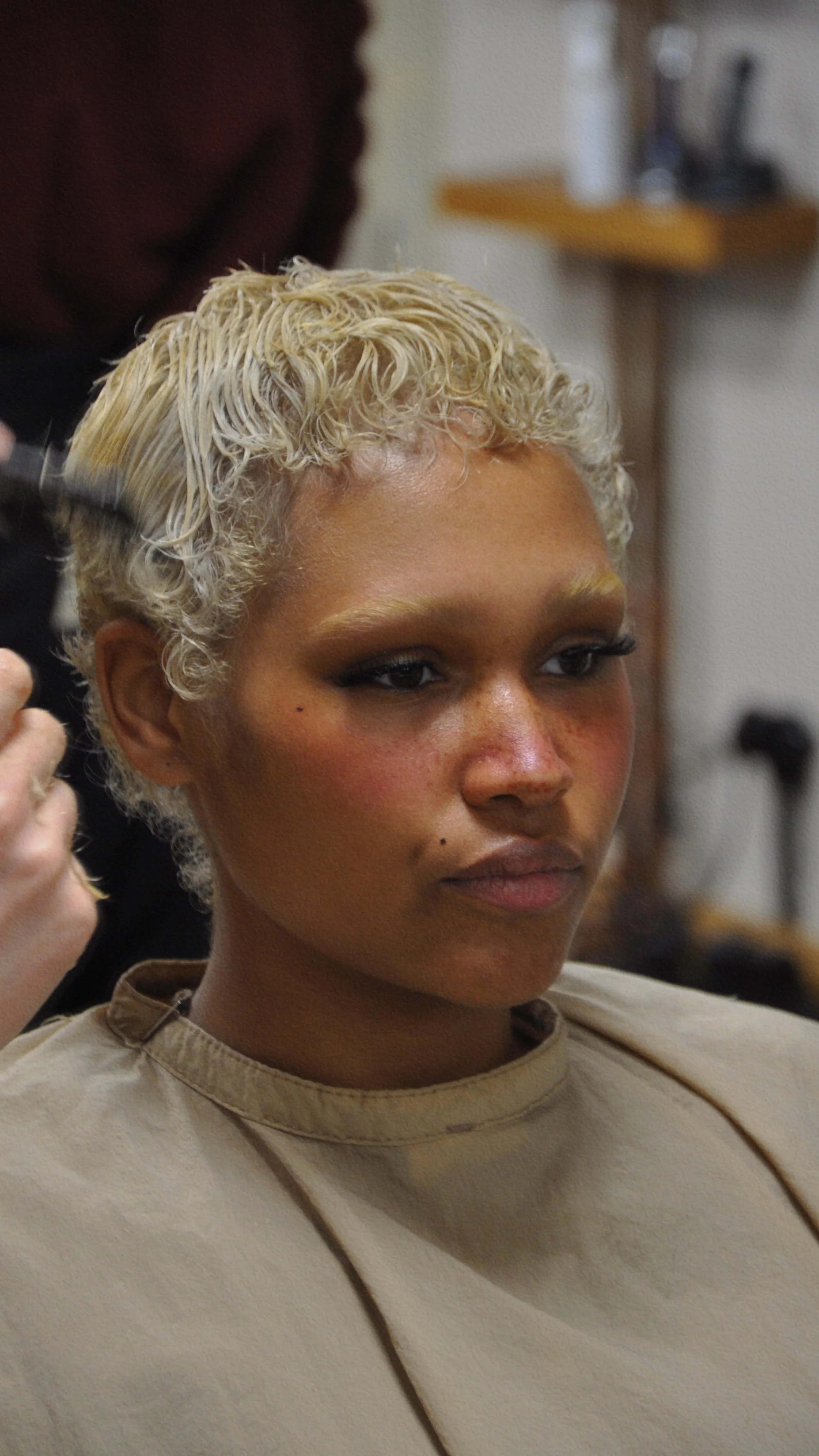 Close-up of a person with short, curly blonde hair getting her hair styled at NeoPrivée Salon in Berlin.