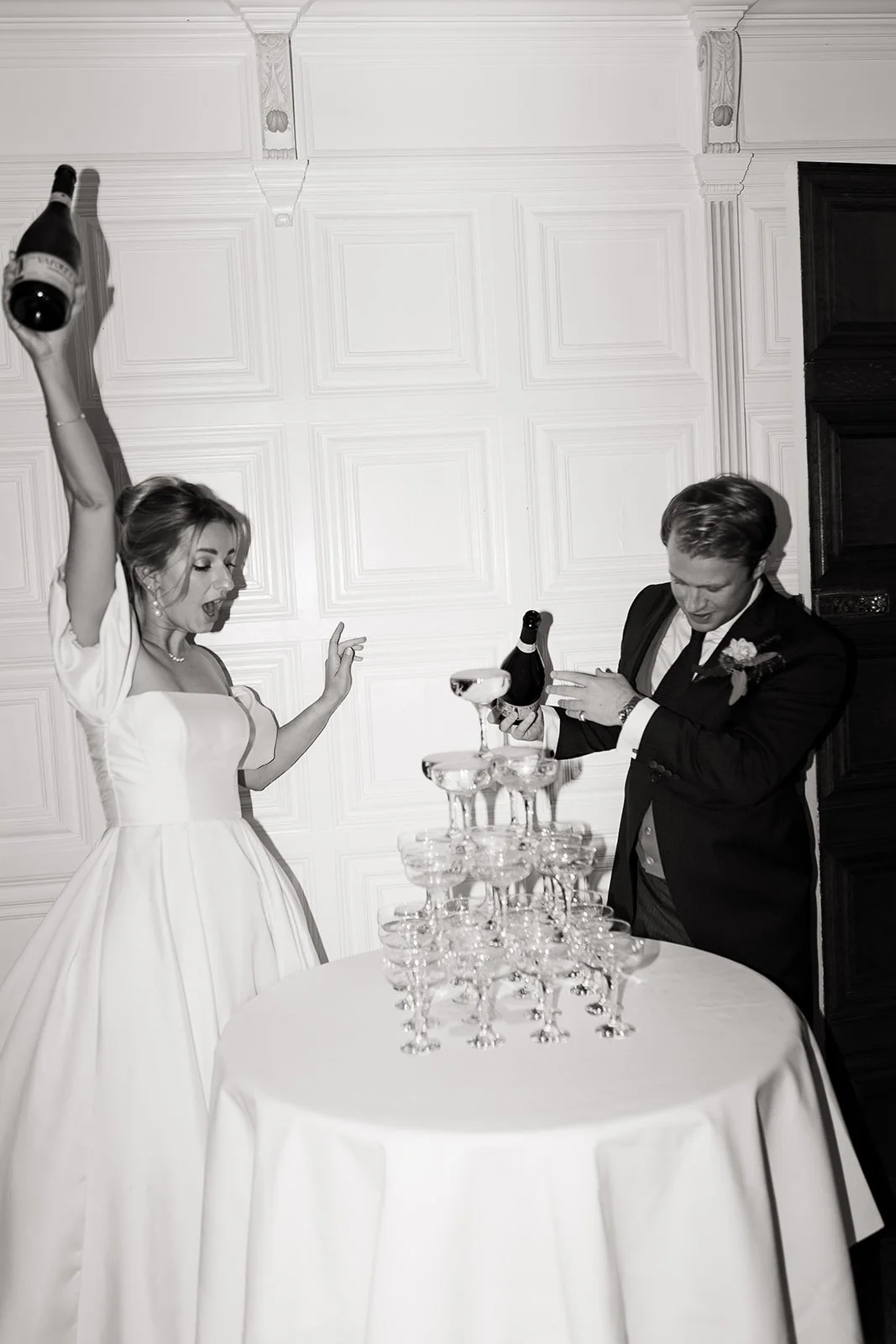 A bride and groom celebrating with a champagne tower at a wedding reception.