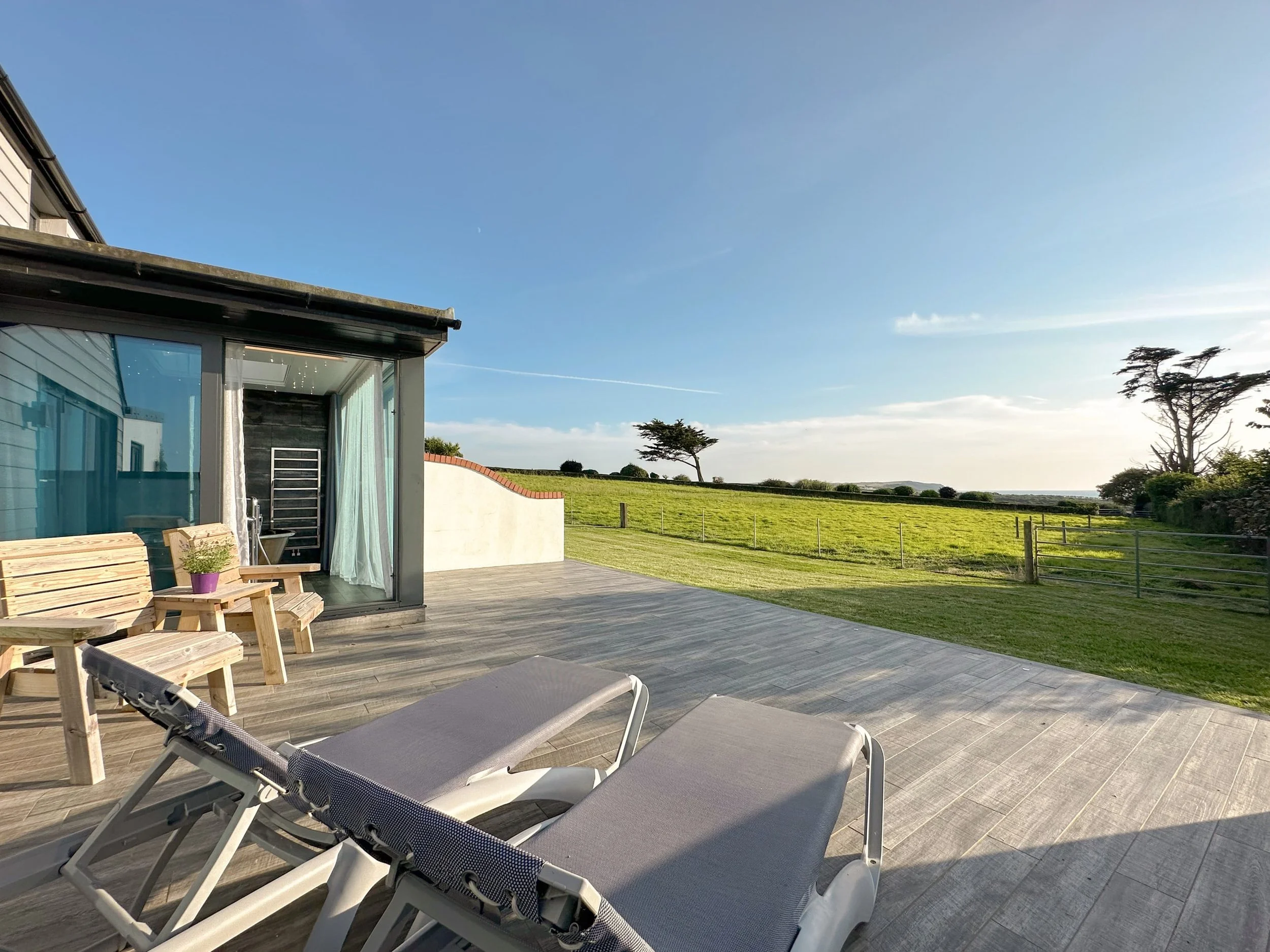 Large patio area with sun loungers and Cornish countryside and sea view