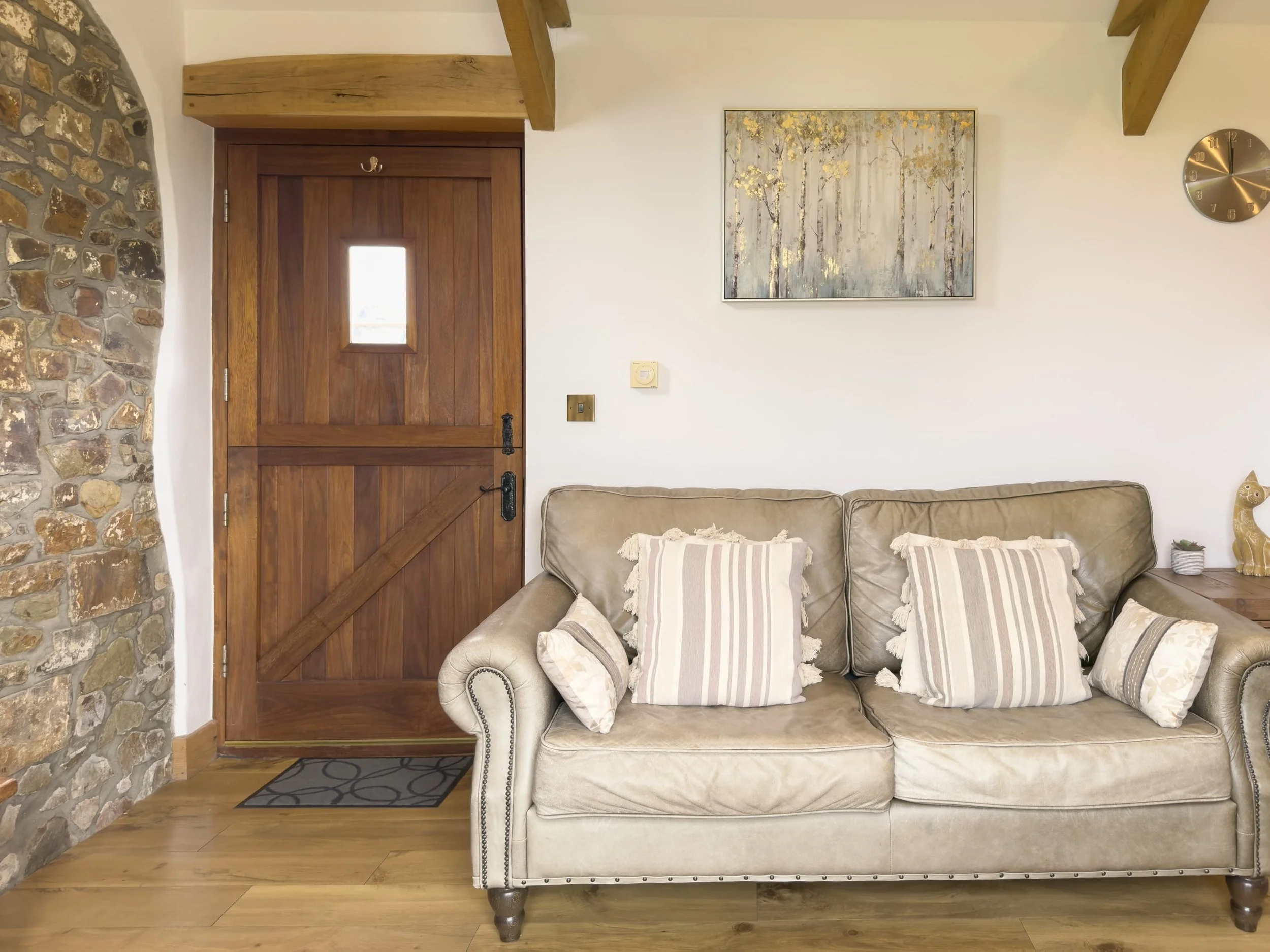 Living area with leather sofa and original exposed stone wall