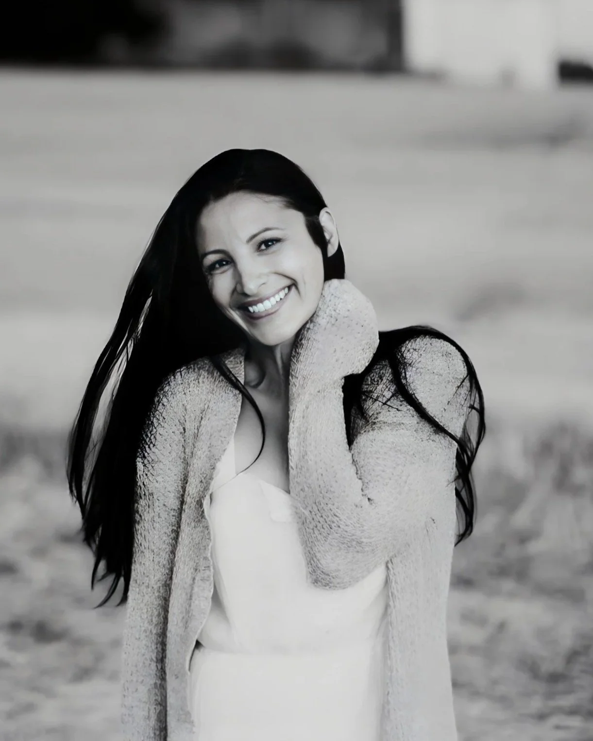 A woman smiling on a beach, black and white photo.