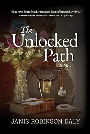 Book cover for 'The Unlocked Path' by Janis Robinson Daly, featuring a bouquet of flowers in a glass vase, a vintage phone, a stethoscope, and a book on a wooden table.
