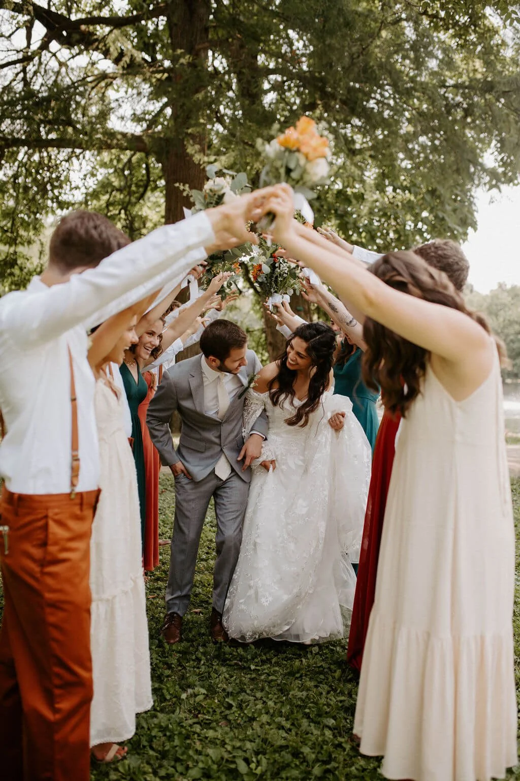 bride and groom with bridal party as they make a tunnel with arms for couple to walk through