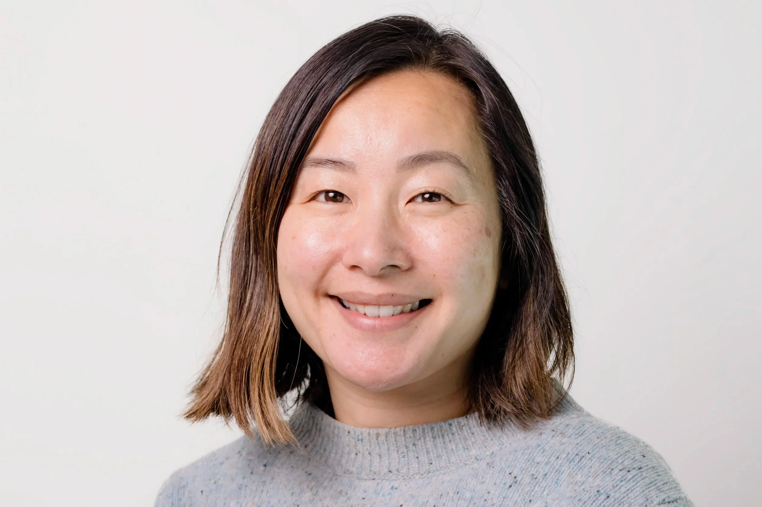 Headshot of Dr Roslyn Le Gautier with short brown hair and a grey jumper.