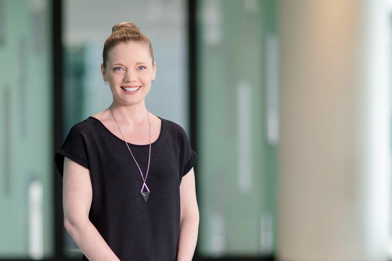 Head shot of Dr Jessica Vanslambrouck with brown hair in a bun and wearing a black top with a necklace.