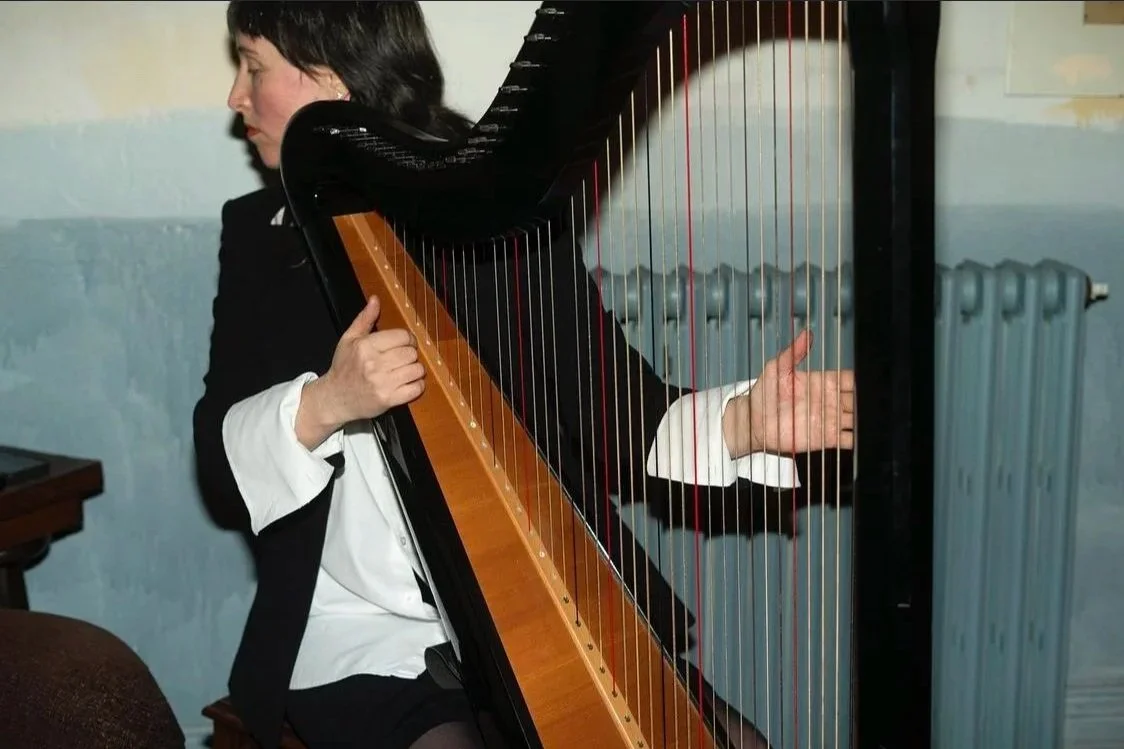 Genevieve Fry playing a harp.