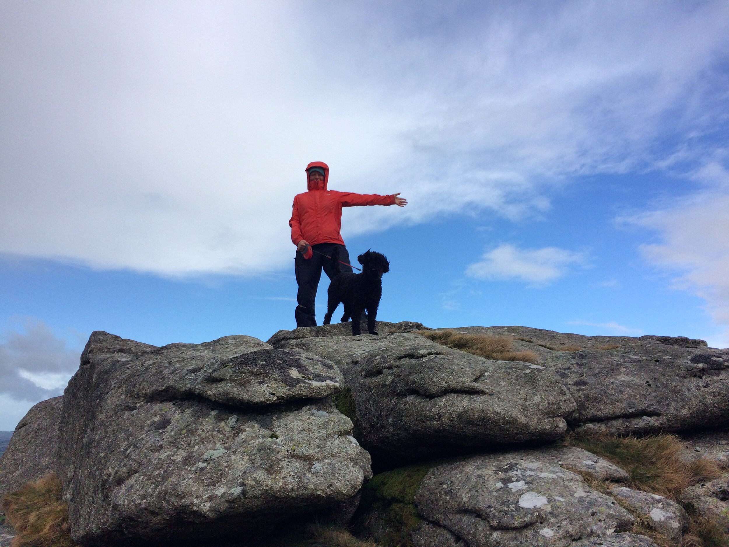 Lucy Spink standing on the top of Dartmoor with her dog