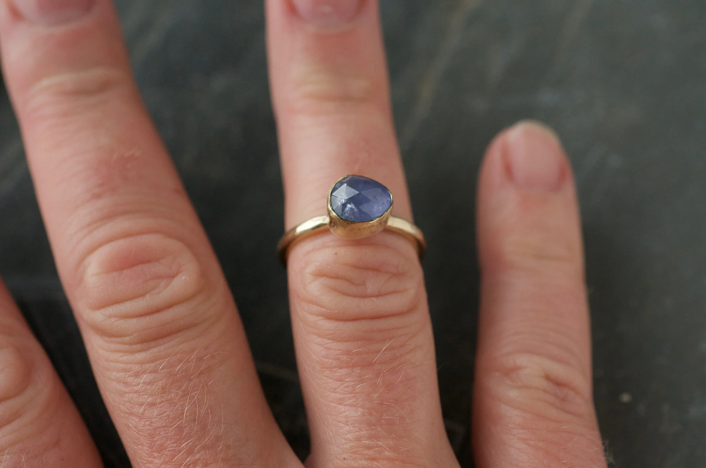 tanzanite and gold ring shown on models finger